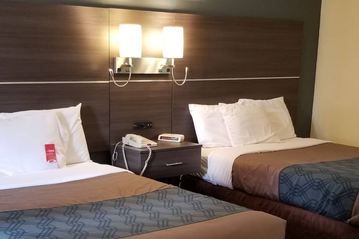Ein Hotelzimmer mit zwei Betten, einem Nachttisch mit Telefon und Wandleuchten.