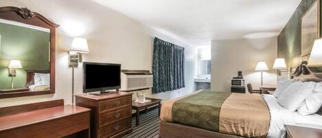 Quarto de hotel com cama, televisão, escrivaninha, espelho e janela com cortinas.