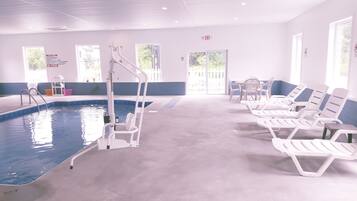 A swimming pool area with a lifeguard stand, lounge chairs, and a clear view of the outdoors through large windows.