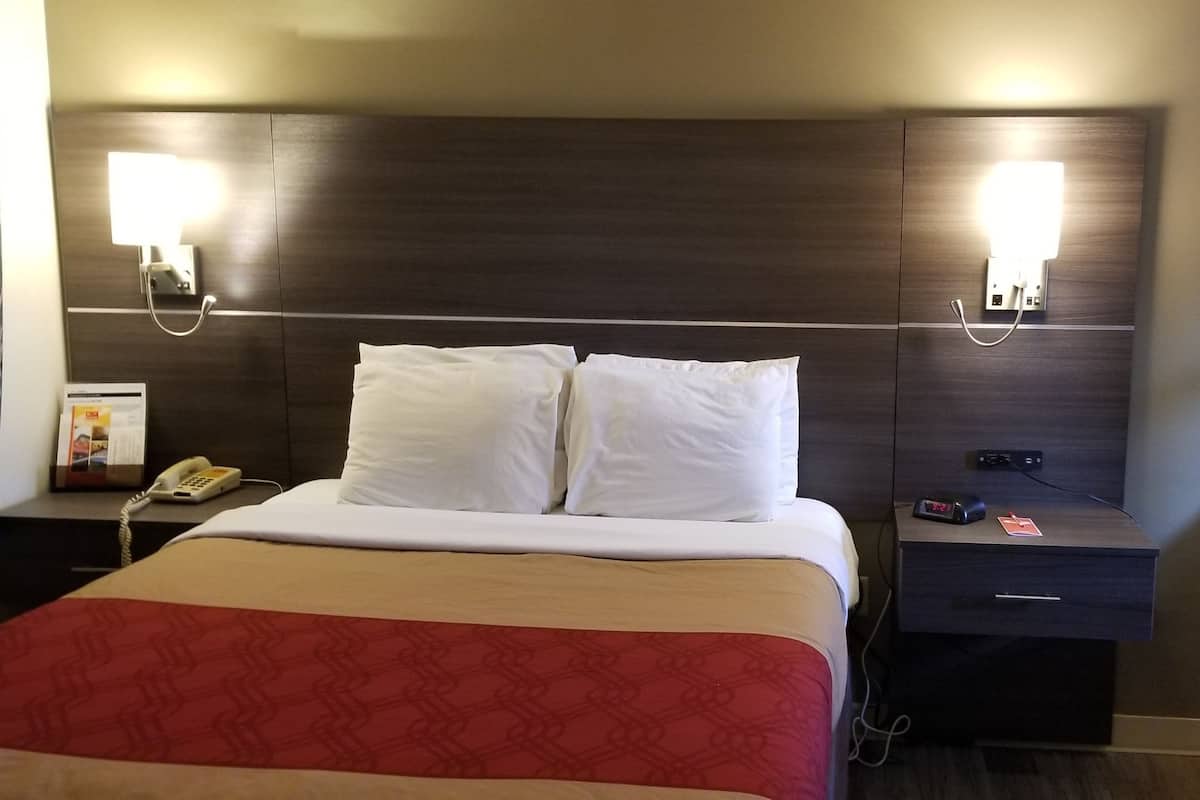 Ein Hotelzimmer mit einem Bett, Nachttischen, einem Sessel und Wandleuchten.