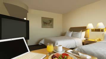 Une chambre d’hôtel avec un lit, une table de chevet, une lampe et un ordinateur portable posé sur un bureau.