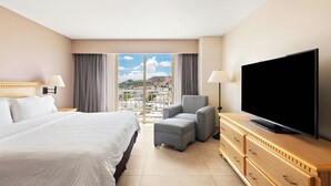 A hotel room with a bed, a TV, a chair, and a view of the city. - Fiesta Inn Express Hermosillo (Hermosillo)