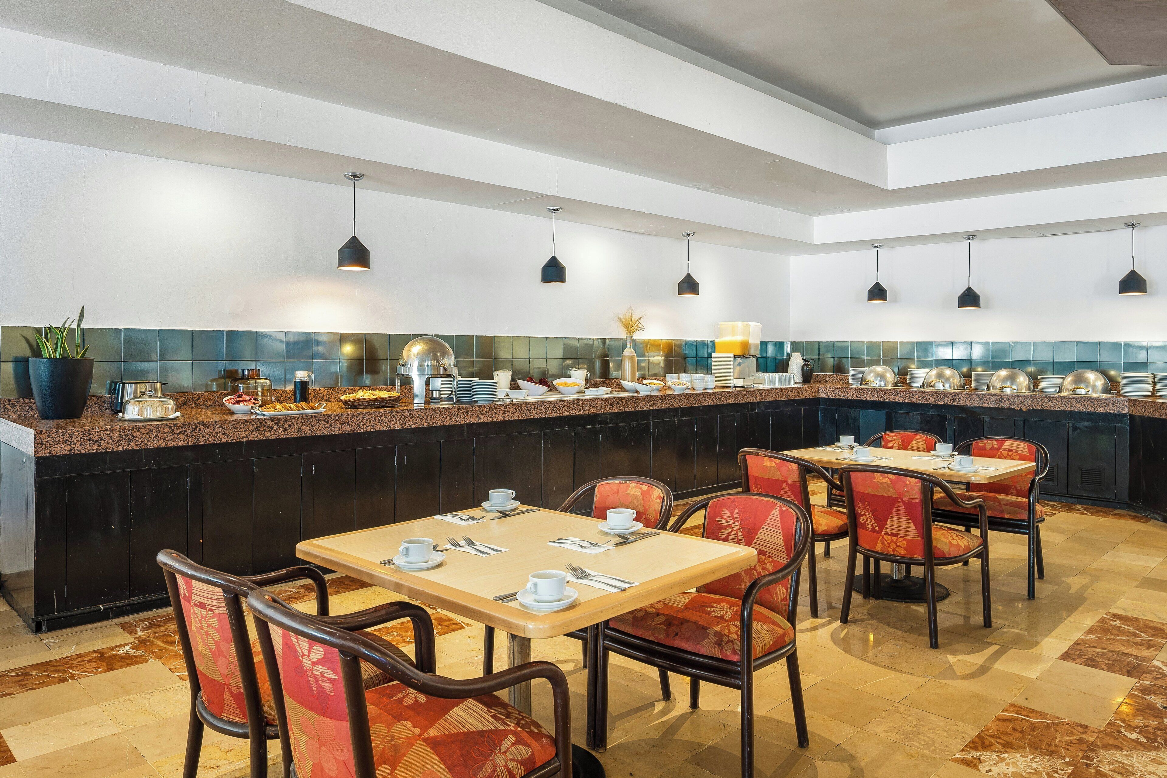 Un restaurante con una barra larga, varias mesas y sillas.