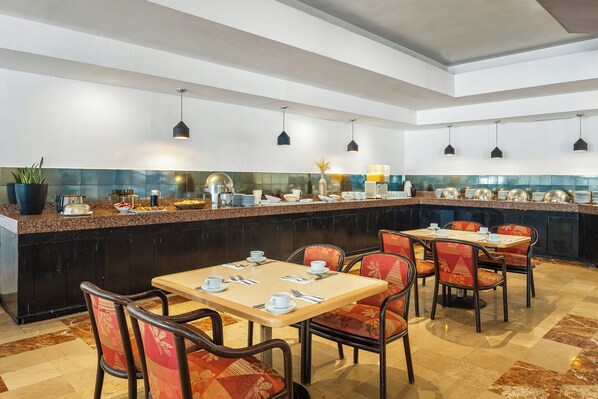 A restaurant with a long counter, multiple tables, and chairs. - Fiesta Inn Express Hermosillo (Hermosillo)