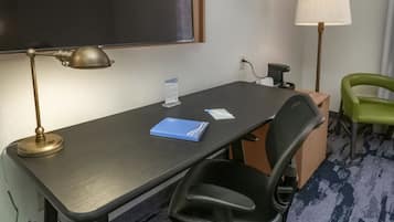 A hotel room with a desk, a chair, a lamp, and a blackboard.