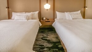 Habitación de hotel con dos camas, una mesita de noche con un teléfono y una lámpara fijada a la pared.