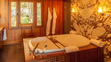 A wooden bathroom with a large bathtub, wooden cabinets, and a stone wall with a heart design.