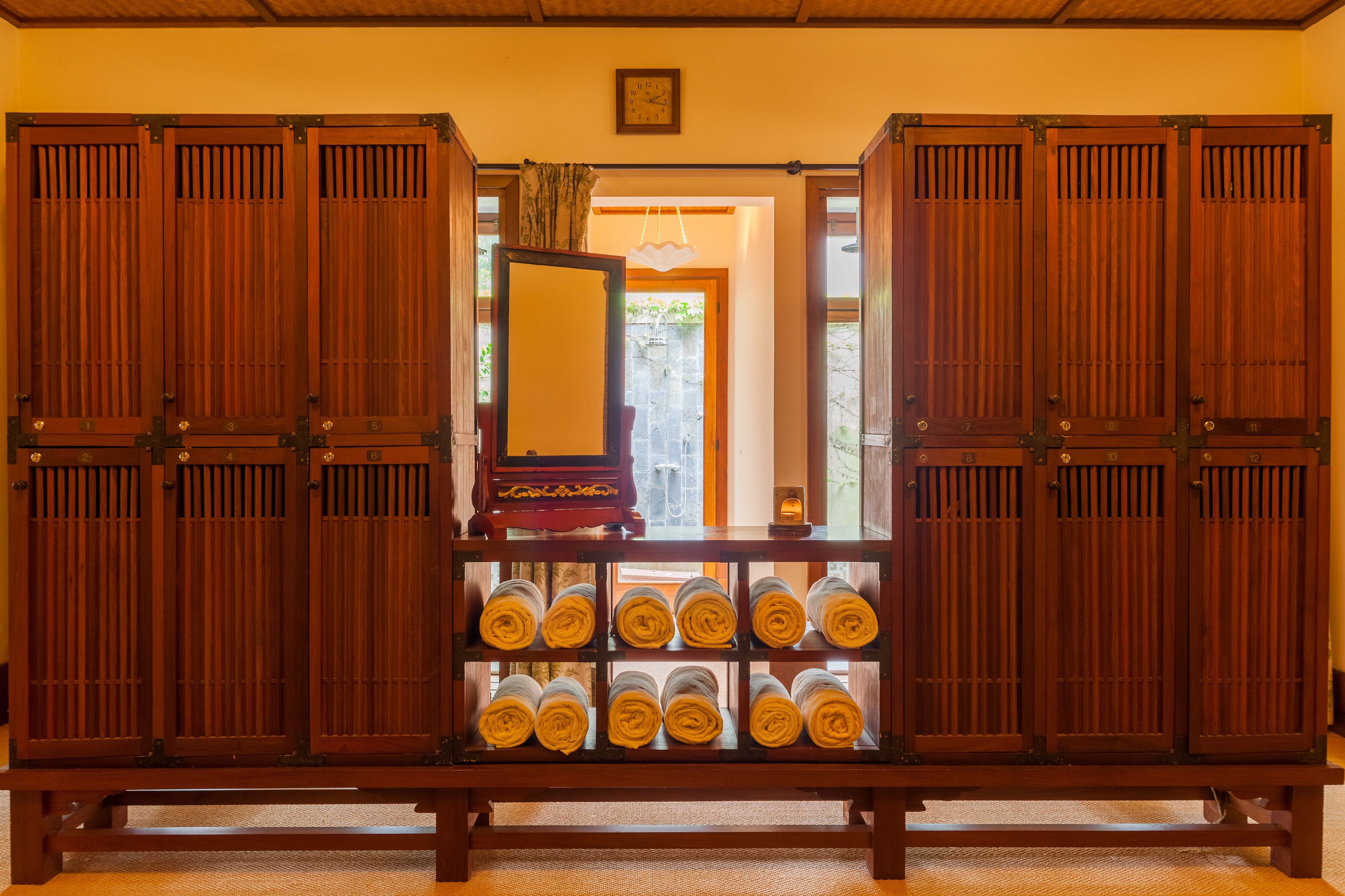 A traditional Japanese room with sliding doors, a wooden bench, and neatly rolled towels.