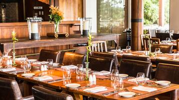 A restaurant with wooden tables and chairs, set with white plates, glasses, and cutlery.