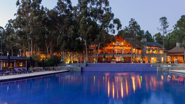 Ein Resort mit großem Swimmingpool, mehreren Gästezimmern und einer gepflegten Rasenfläche.