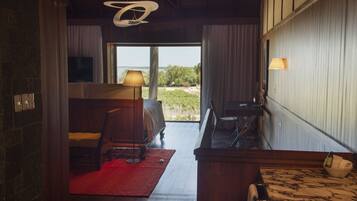 A bedroom with a large window, a bed, a desk, and a chair.