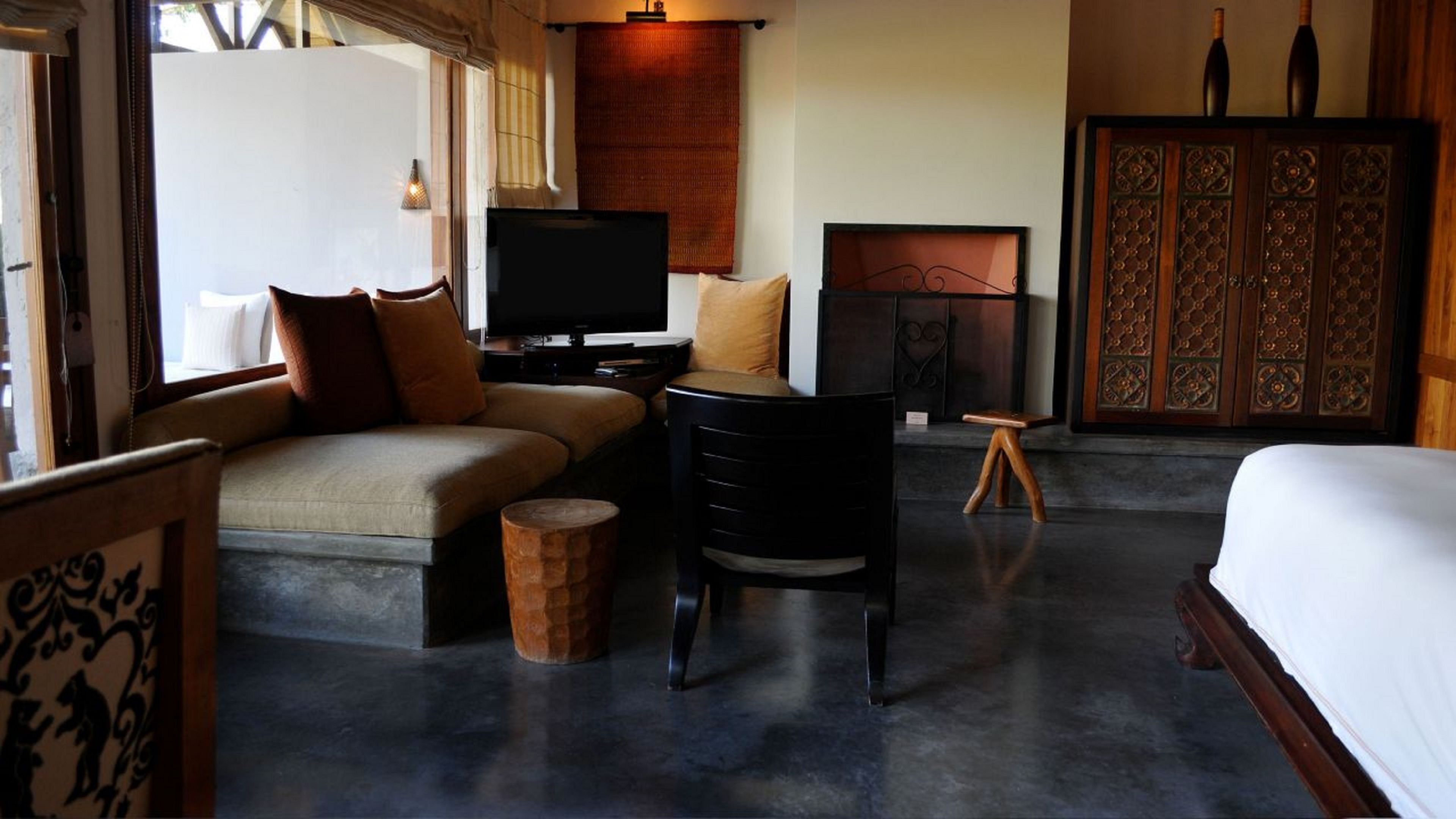 A hotel room with a sofa, a small table, a television, a fireplace, and a wardrobe.