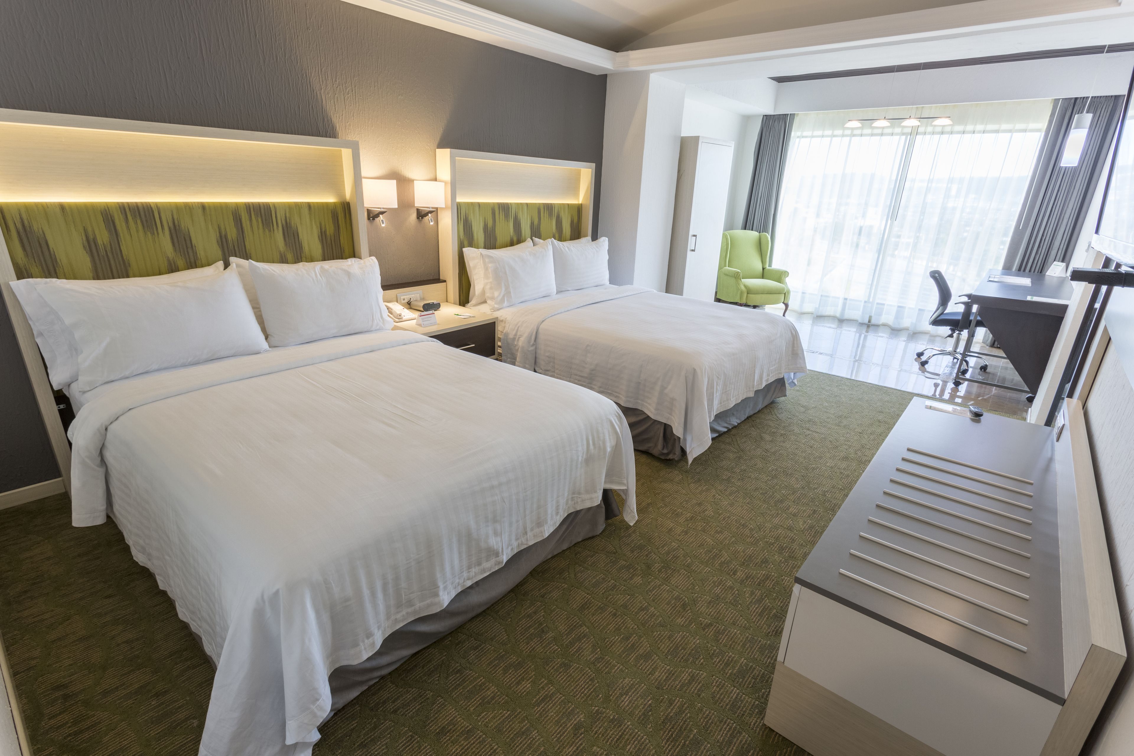 Quarto de hotel com duas camas, uma escrivaninha e uma cadeira.