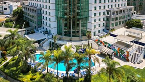 A Holiday Inn hotel with a central courtyard featuring a swimming pool, surrounded by palm trees and lounge chairs. - Holiday Inn Queretaro Zona Diamante by IHG (Querétaro)