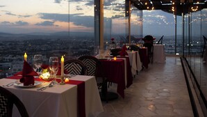 A restaurant with tables set for dining, featuring a cityscape view through large windows. - Holiday Inn Queretaro Zona Diamante by IHG (Querétaro)