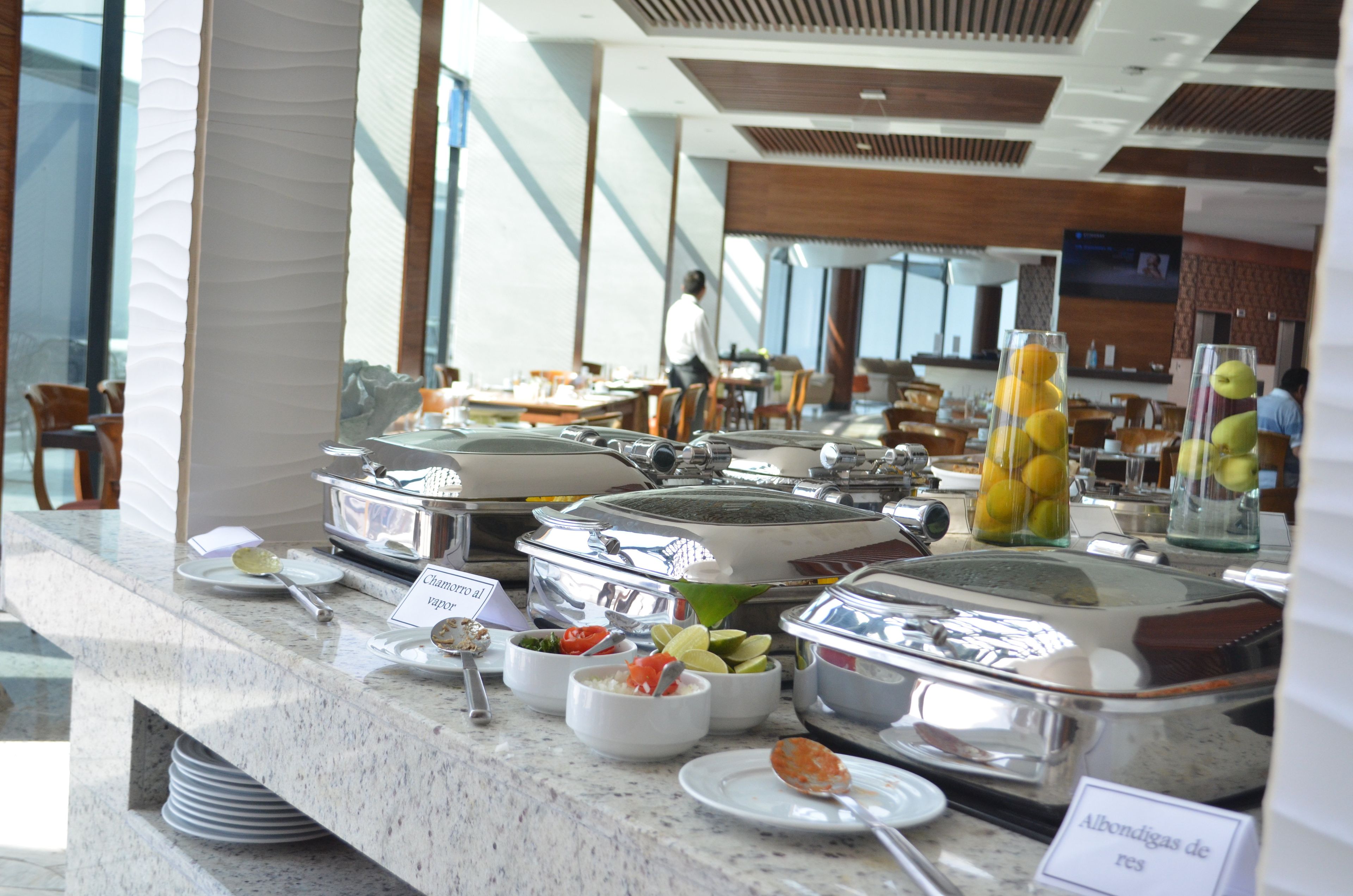 A buffet area with various food containers, including a sign for 'Chamarro al vapor'.