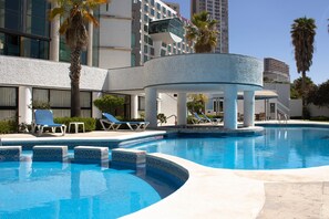 A swimming pool with lounge chairs and palm trees, surrounded by modern buildings. - Holiday Inn Queretaro Zona Diamante by IHG (Querétaro)