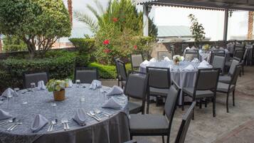 Un espace extérieur aménagé pour les repas, avec des tables rondes disposées pour accueillir quatre personnes, entourées de chaises.
