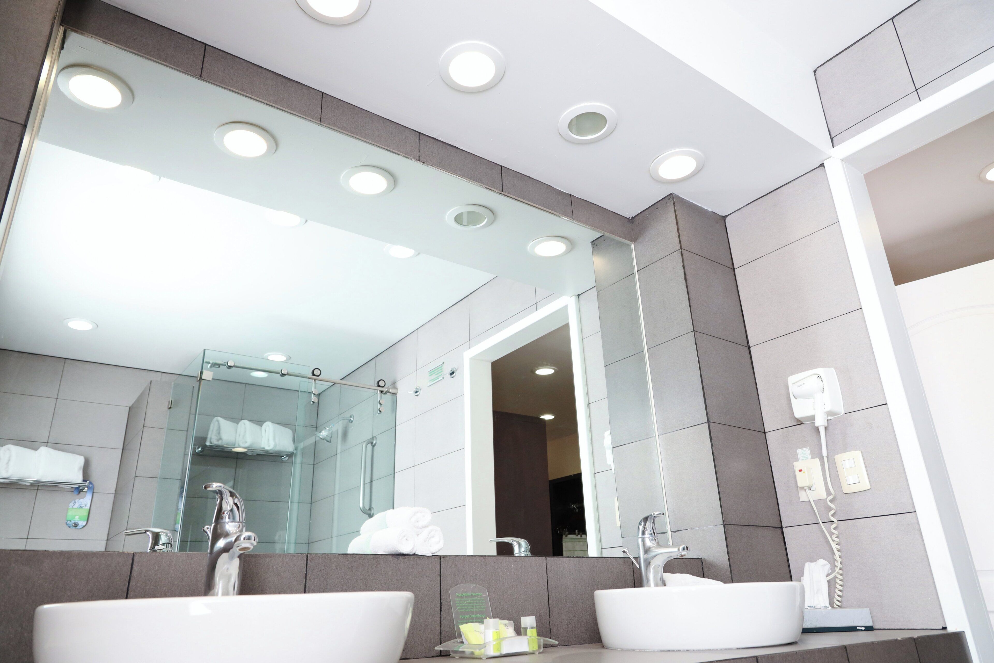 Un baño moderno con dos lavabos, cabina de ducha de vidrio y un espejo grande.