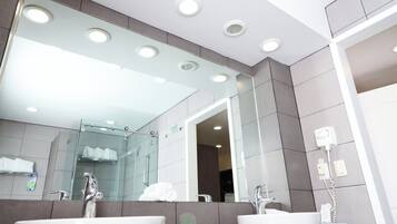Un baño moderno con dos lavabos, cabina de ducha de vidrio y un espejo grande.
