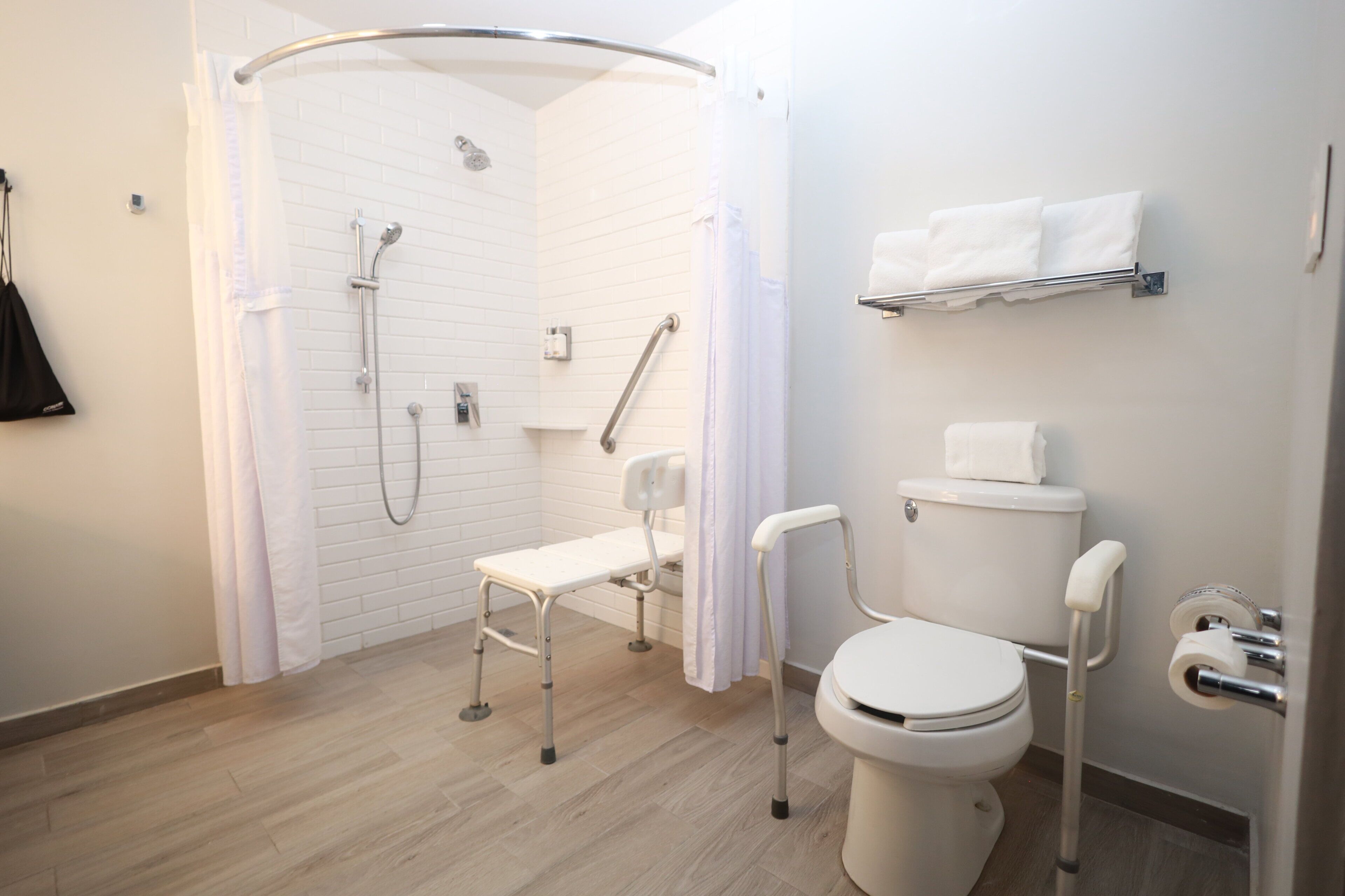 Un baño moderno con ducha, inodoro y un asiento accesible para sillas de ruedas.