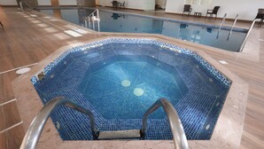 An indoor swimming pool with a tiled floor and a pool ladder.