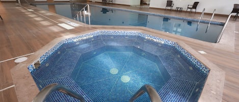 An indoor swimming pool with a tiled floor and a pool ladder.
