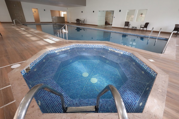 An indoor swimming pool with a tiled floor and a pool ladder.