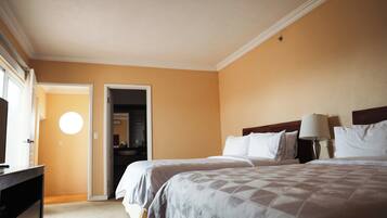 Een hotelkamer met twee bedden, een dressoir, een lamp en een deur naar de badkamer.
