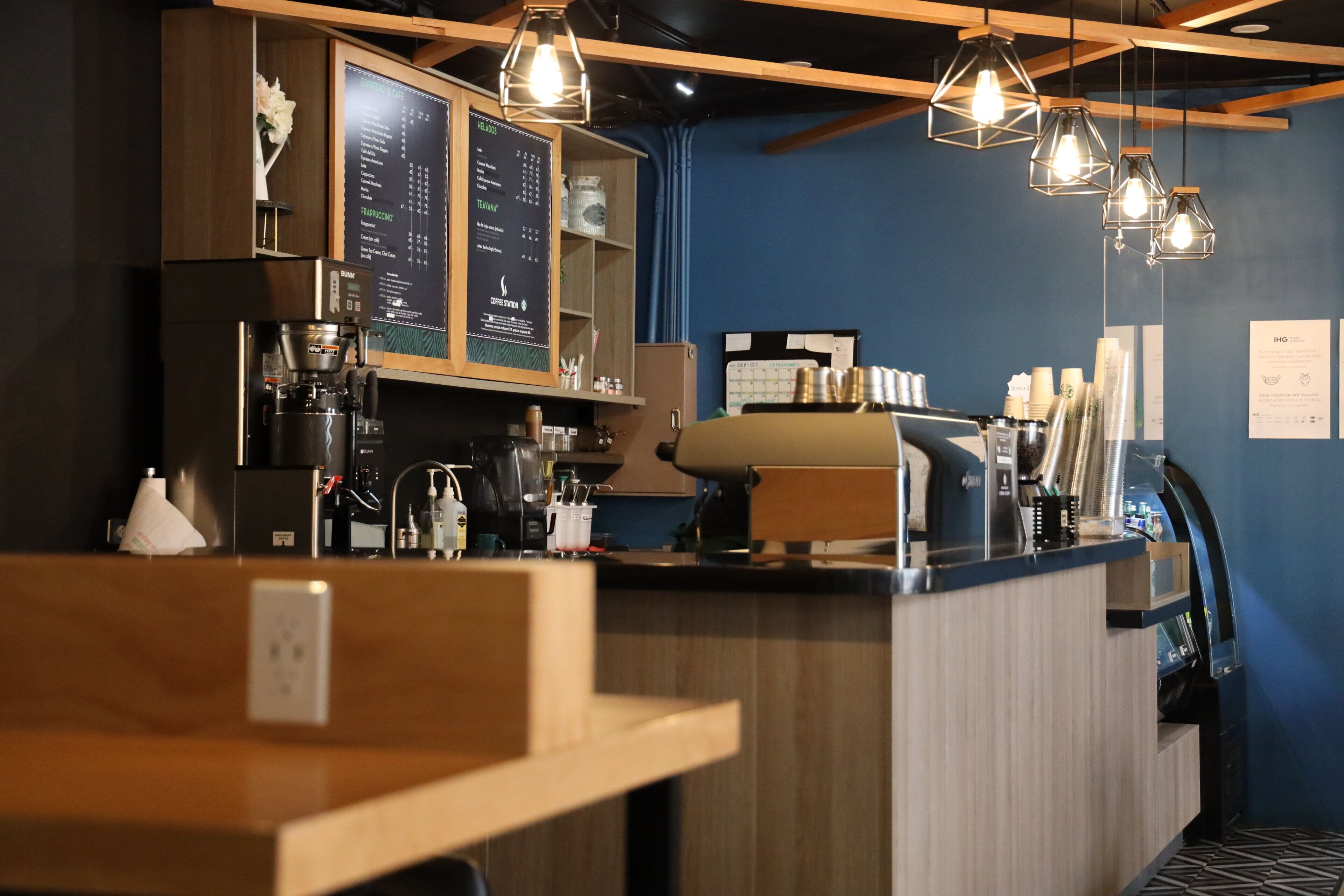 A coffee shop interior with a menu board, espresso machine, and hanging pendant lights.