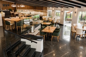Un restaurante moderno con diversas opciones de asientos, incluyendo mesas y cabinas, y una escalera que lleva a un nivel superior.
