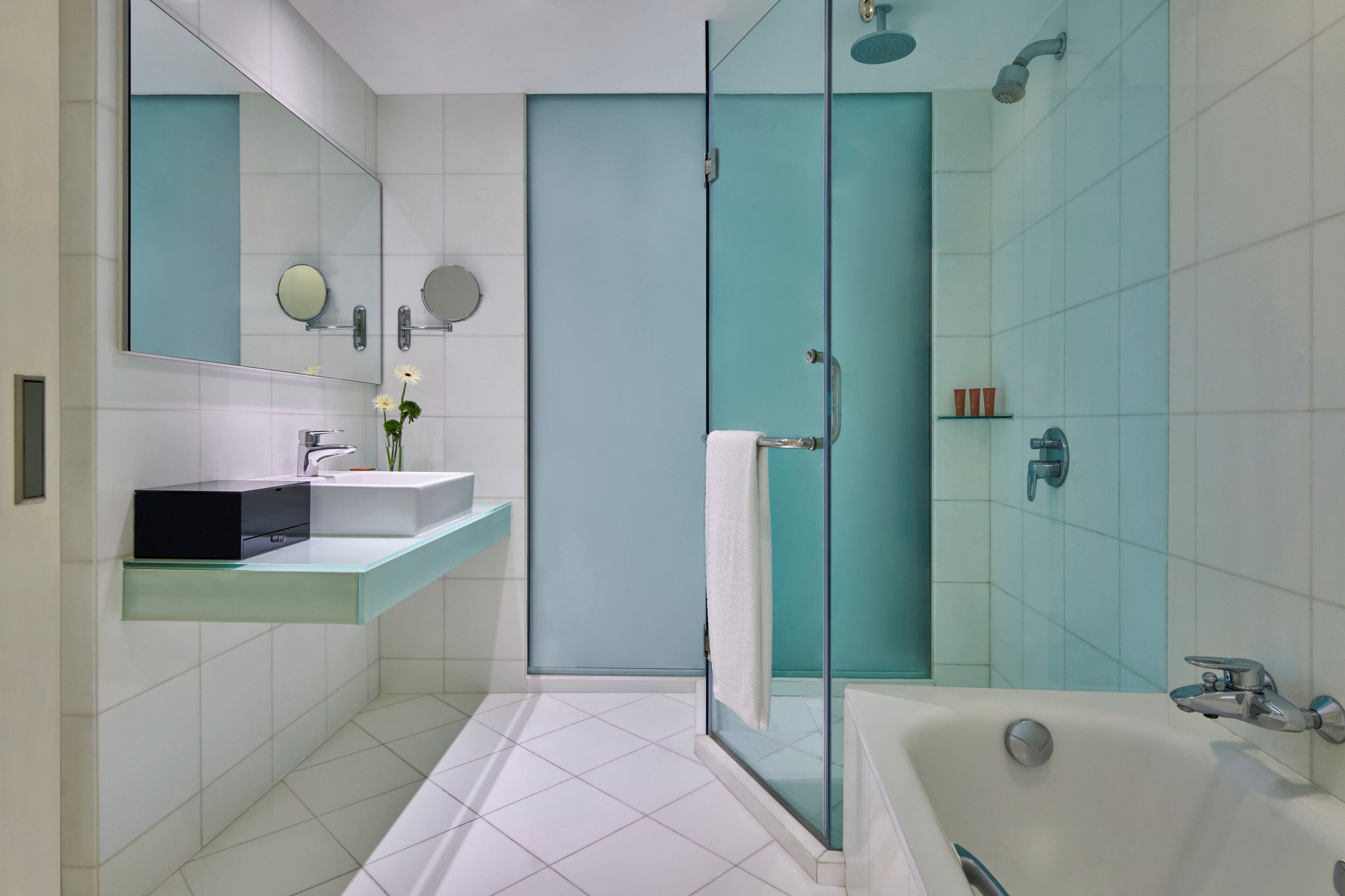 Un bagno moderno con cabina doccia in vetro, una vasca da bagno bianca e un mobile lavabo con specchio e lavandino.
