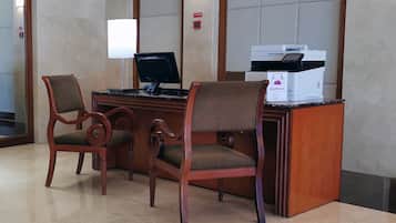 A reception desk with a computer, two chairs, and a printer.