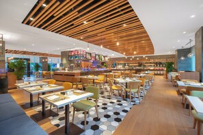 A modern restaurant with a variety of seating options, including tables and booths, and a bar area in the background. - Crowne Plaza Zhuhai City Center by IHG (Zhuhai)