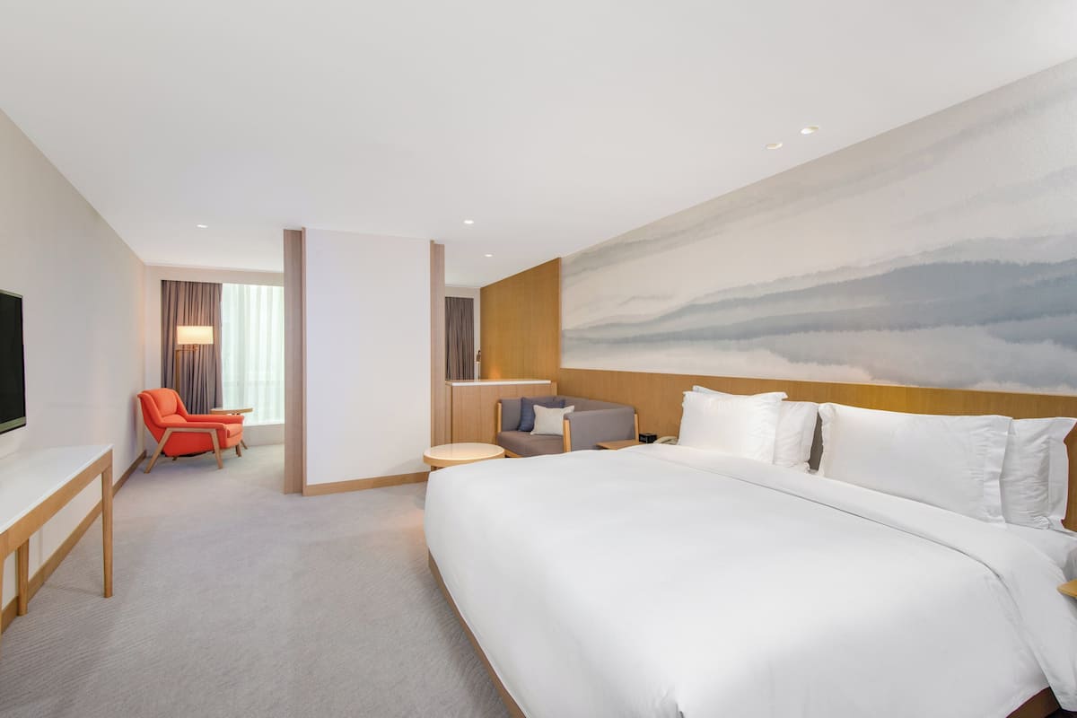 Ein Hotelzimmer mit einem großen Bett, einem Schreibtisch, einem Stuhl und einem Fernseher.