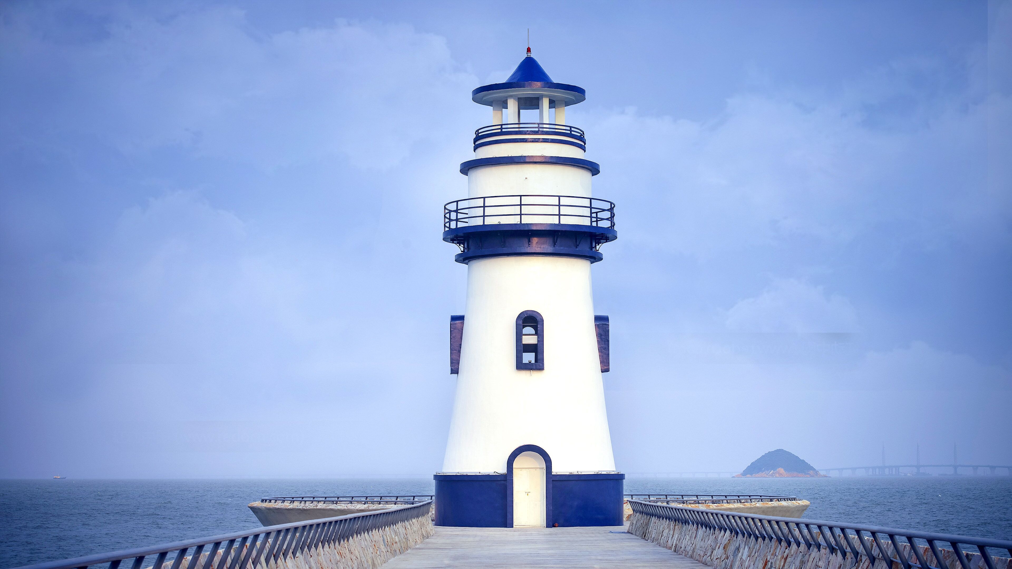 Un faro con vista despejada al mar y una isla distante.