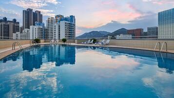 Una piscina al aire libre, sombrillas, sillones reclinables de piscina