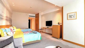 Una habitación de hotel con cama, escritorio, televisor y una pequeña mesa.