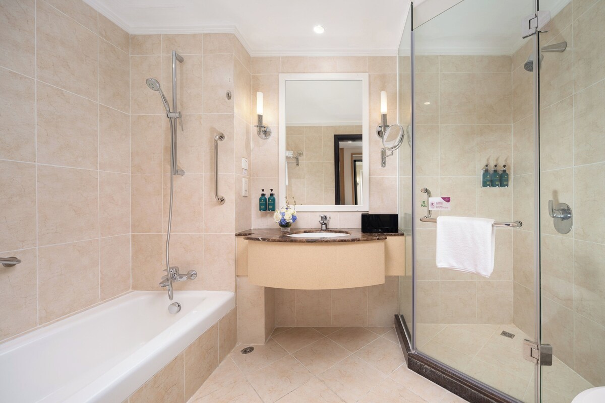 A modern bathroom with a bathtub, sink, and glass-enclosed shower.