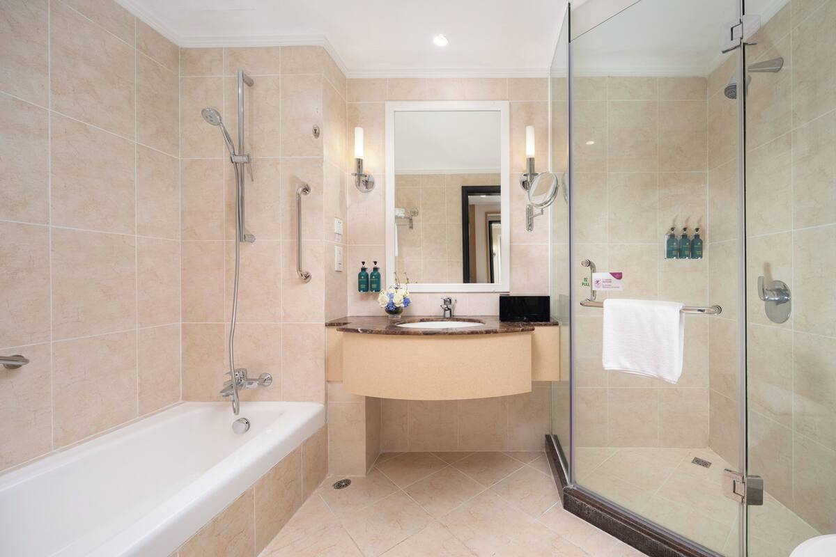 A modern bathroom with a bathtub, sink, and glass-enclosed shower.