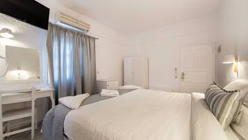 Una habitación de hotel con cama, escritorio con espejo, armario y una puerta.