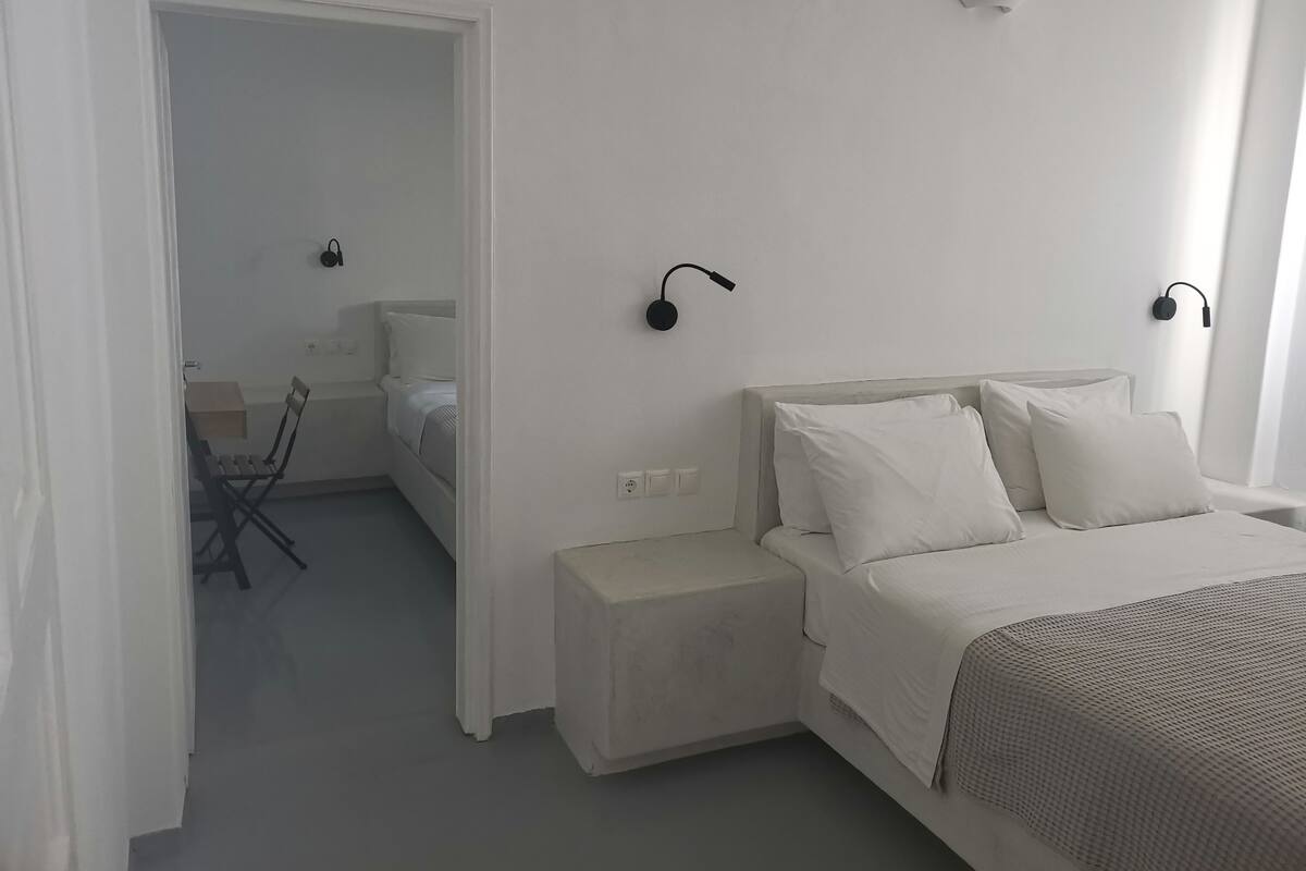 A minimalist bedroom with a bed, bedside tables, and a chair.