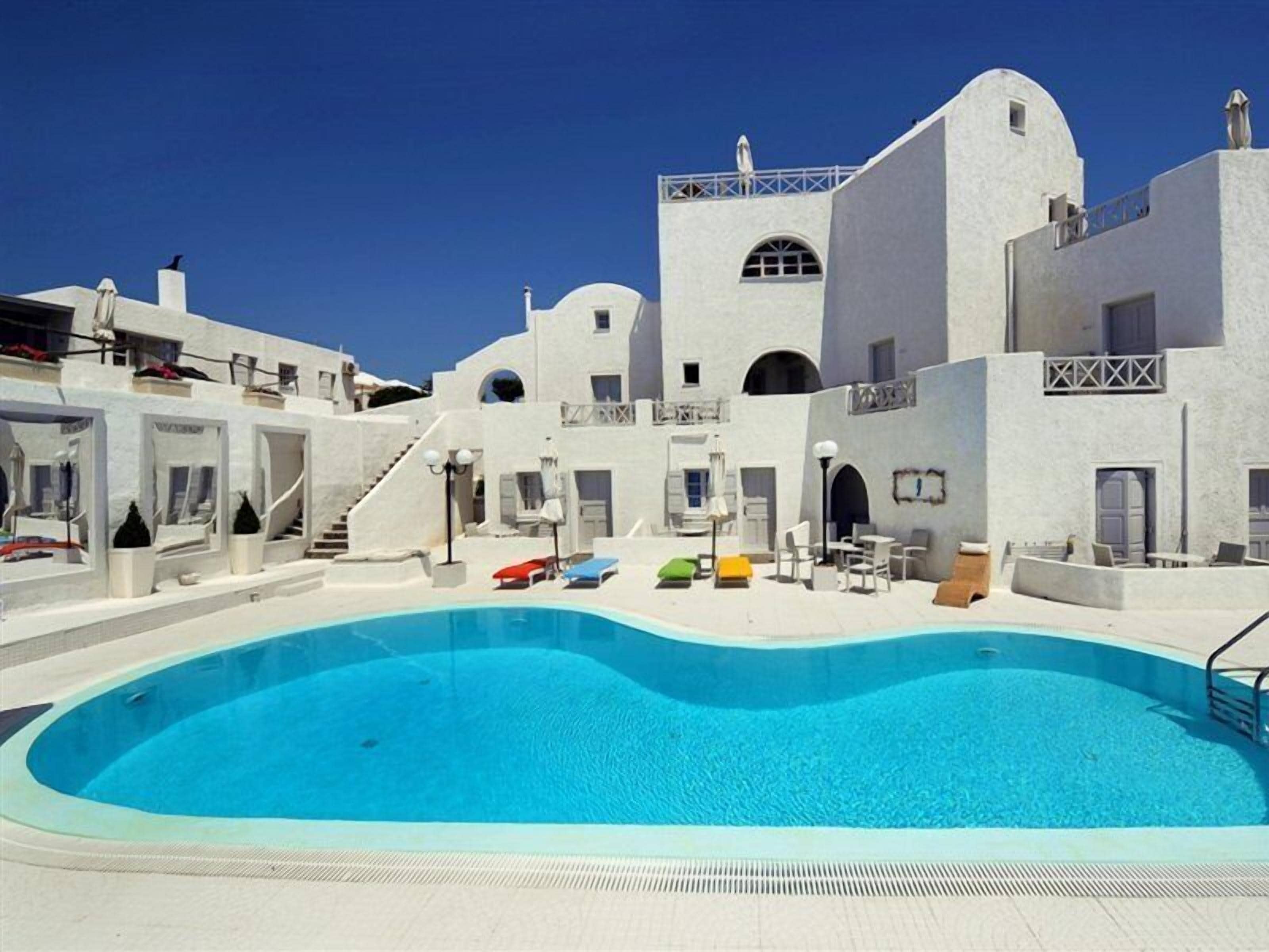 Een buitenzwembad, parasols bij het zwembad en ligstoelen