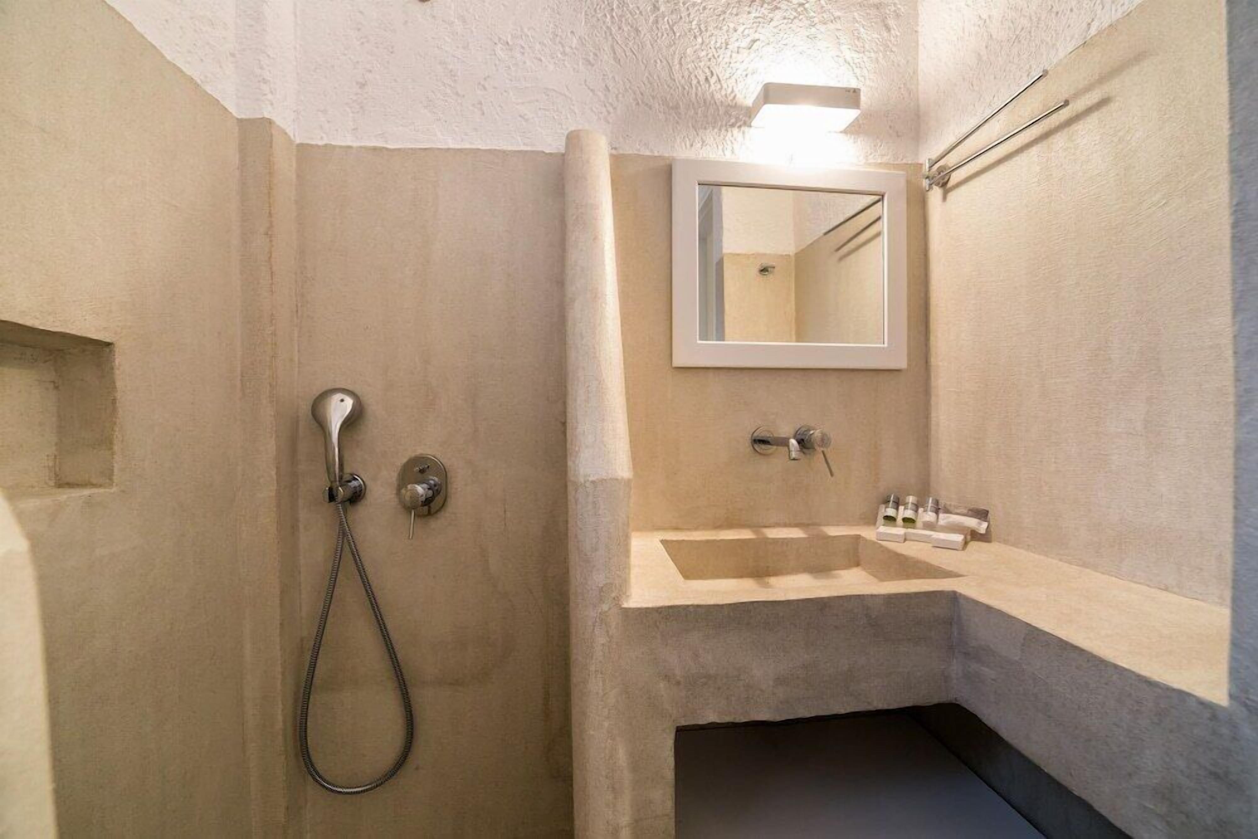 Un baño con ducha, lavamanos y espejo.