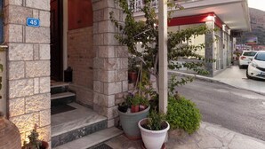 A hotel entrance with stone architecture, a signboard for Monemvasia Rooms, and potted plants on the sidewalk. - Mpalkoni Sti Monemvasia (Monemvasia)
