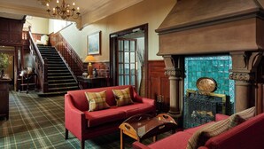 Un interior tradicional con un sofá rojo, una escalera y una chimenea.