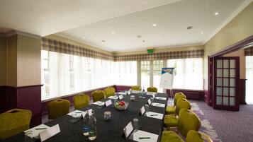 A conference room with a long table, chairs, nameplates, water bottles, and a whiteboard.