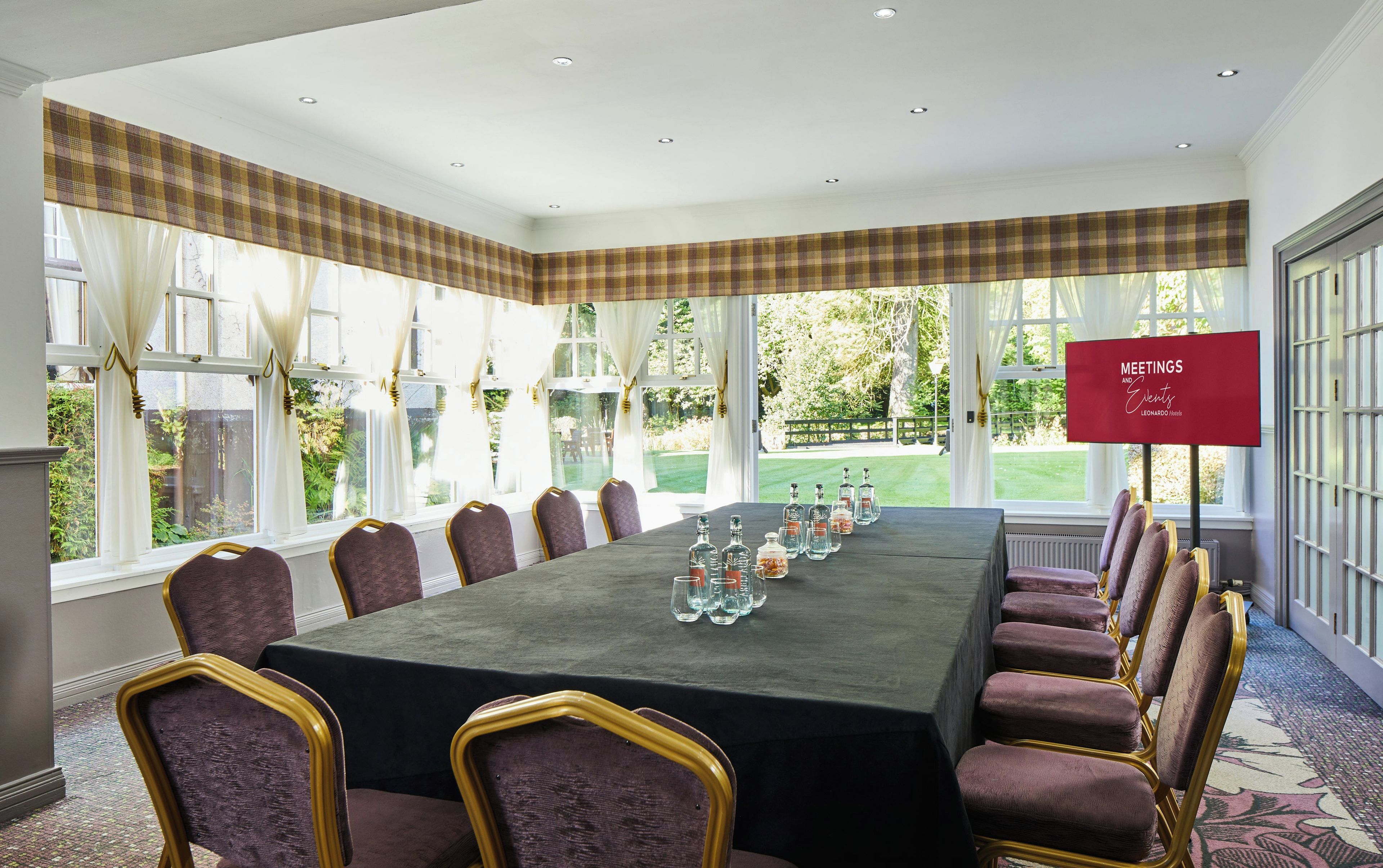 A meeting room with a long table, chairs, and a sign indicating it's for meetings and events.