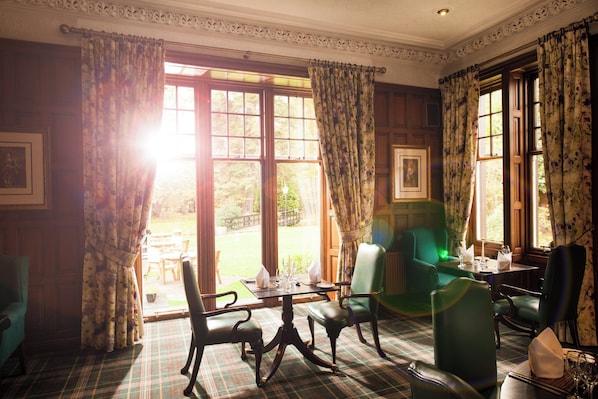 A room with a plaid carpet, green upholstered chairs, a table with a vase, and a window with floral curtains. - Leonardo Boutique Huntingtower Perth (Perth)