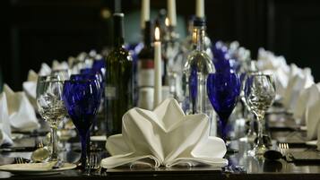A table set for a formal dinner with wine glasses, a centerpiece, and candles.